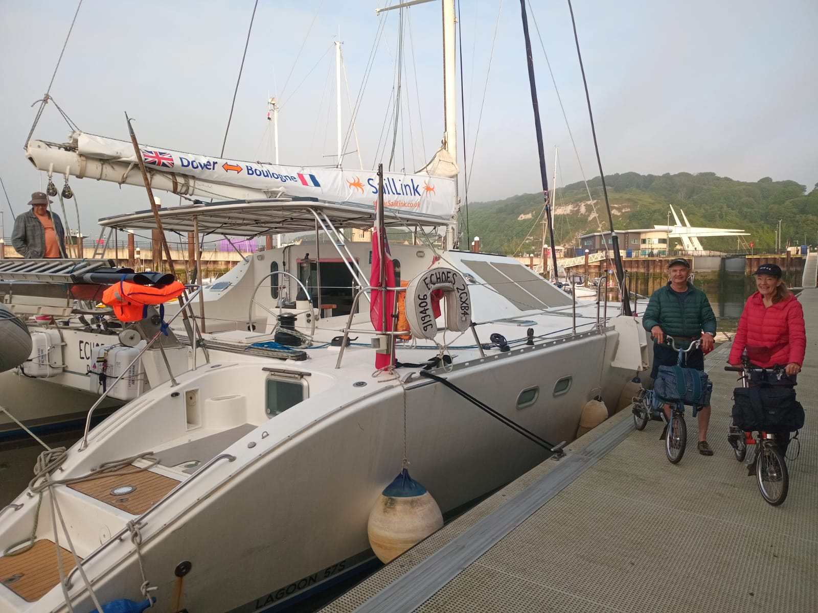 Cyclists with their bikes on the pontoon next to the SailLink catamaran at Dover Marina