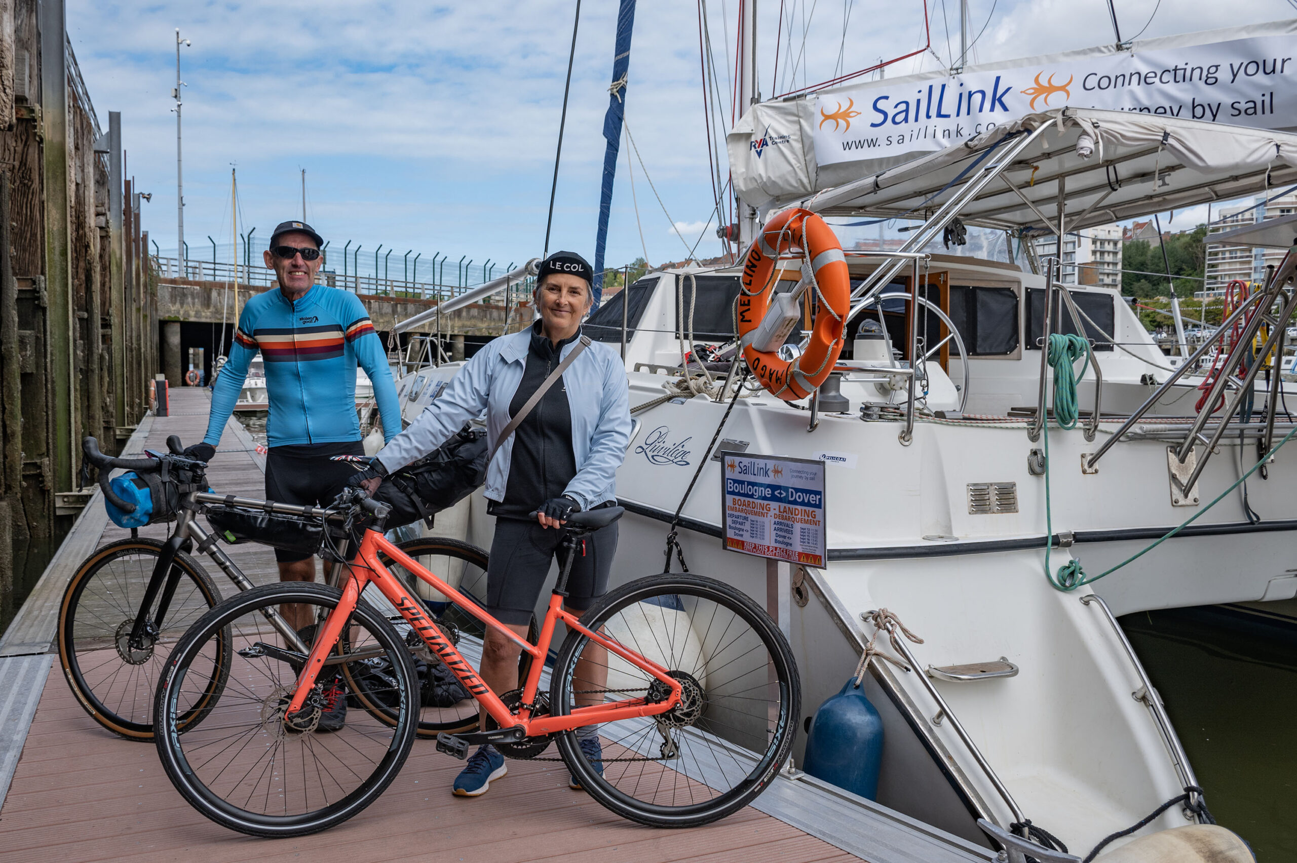 Deux cyclistes et leurs vélos sur le ponton, à côté du catamaran de test utilisé pour les traversées pilotes SailLink de 2022 entre Boulogne-sur-Mer et Douvres